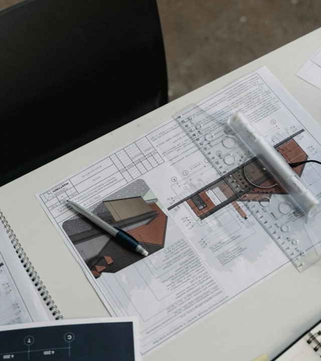 Top view of architectural blueprints and drafting tools on a workspace desk.